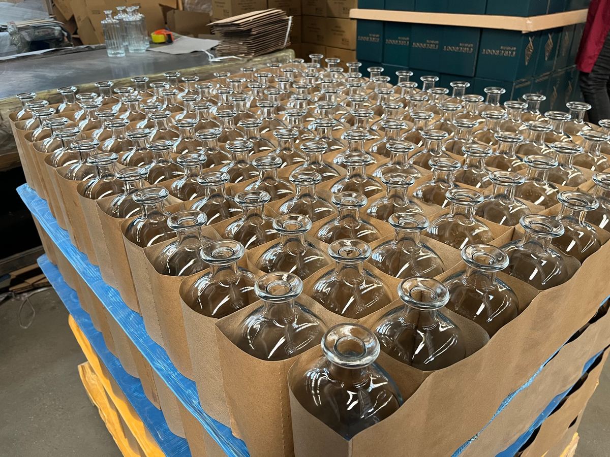 Palletized glass bottles with carton partitions and wrapping for export breakage control