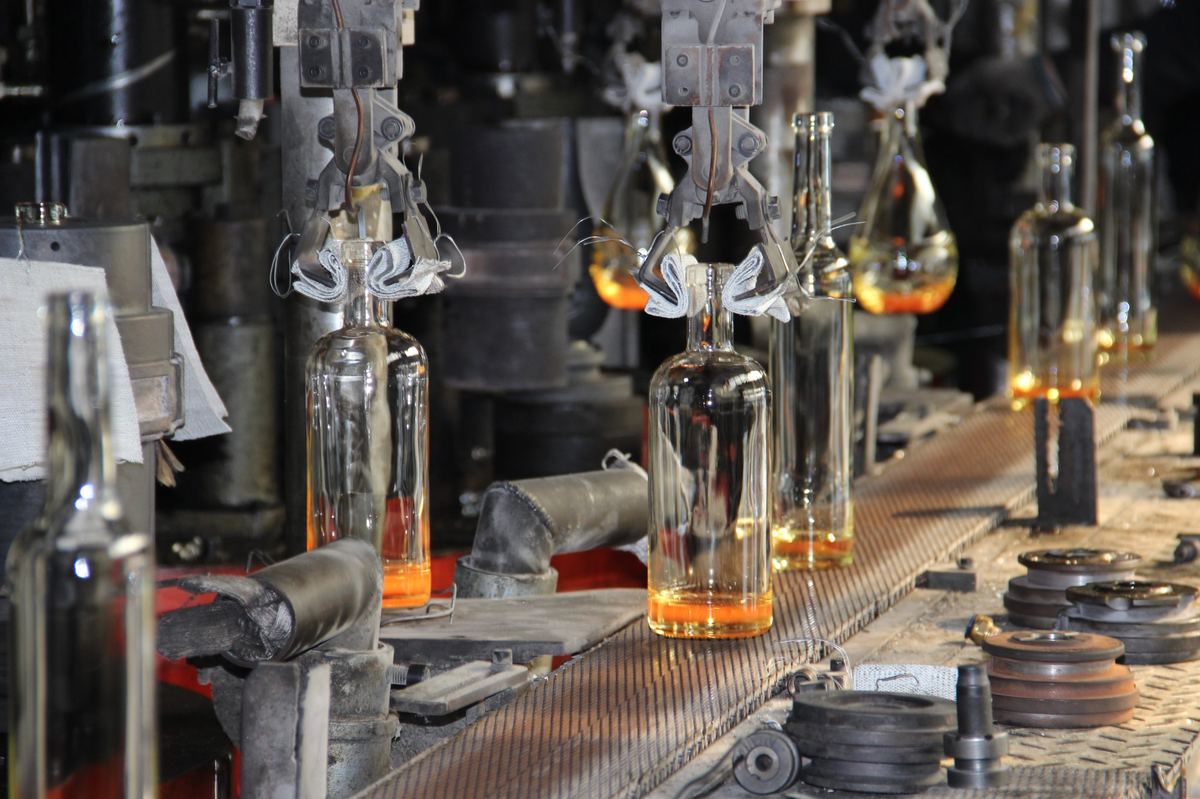 Hot-end glass bottle forming process showing consistent bottle neck and finish production
